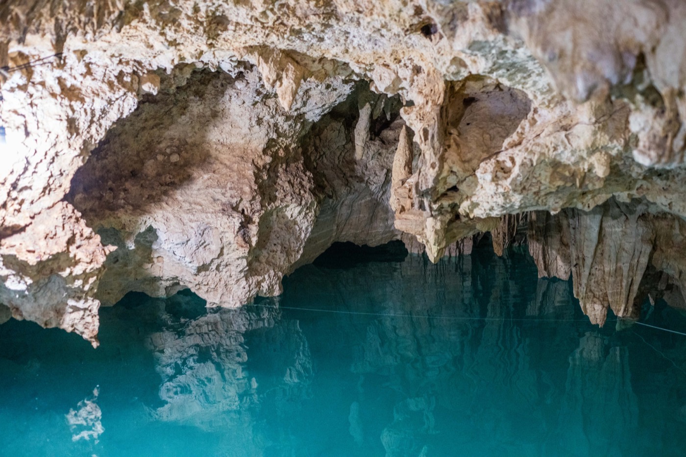 Caverna con estalactitas sobre agua turquesa