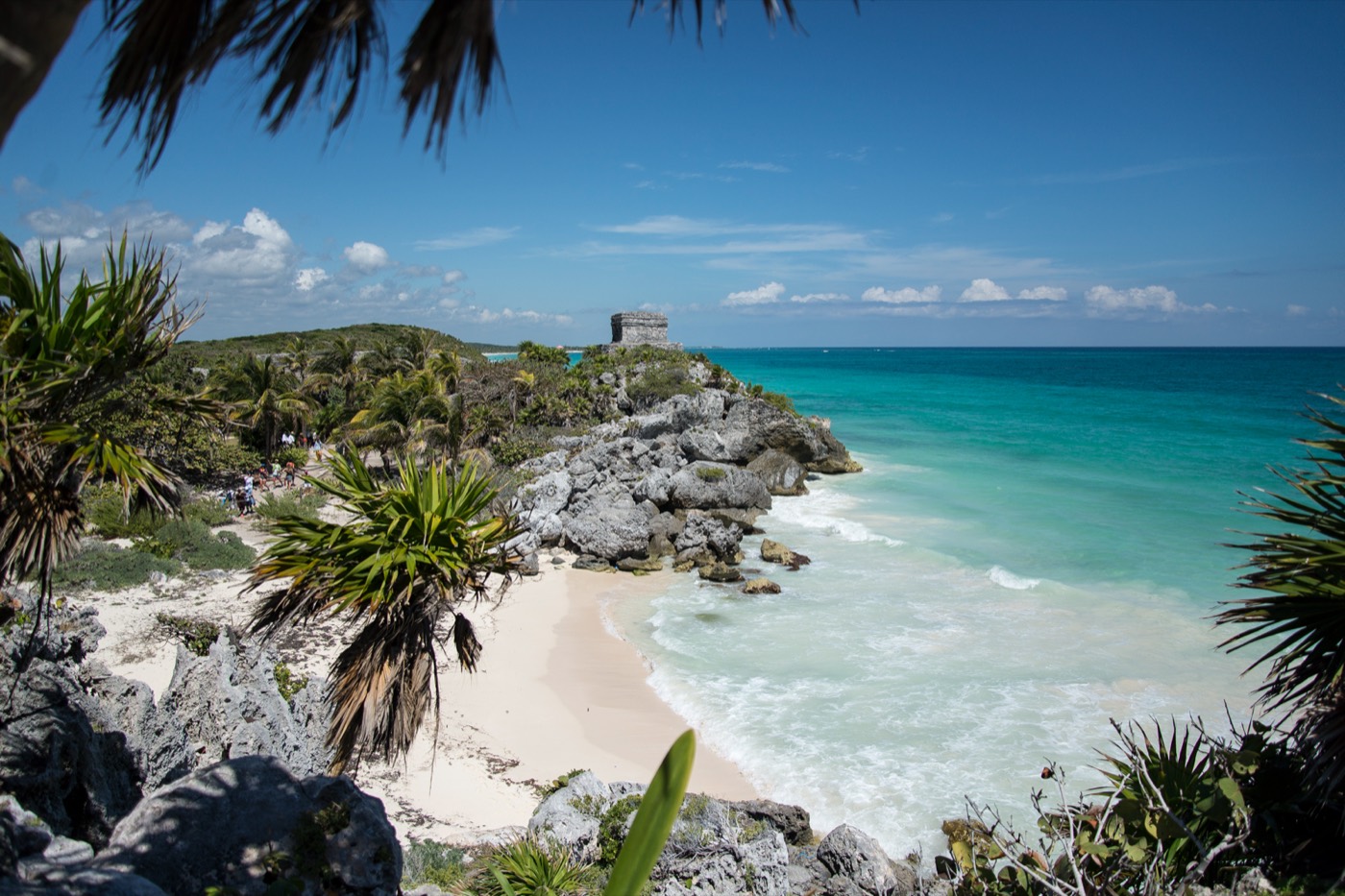 El Castillo de Tulum sobre el acantilado con la playa y el mar Caribe enmarcados por palmeras