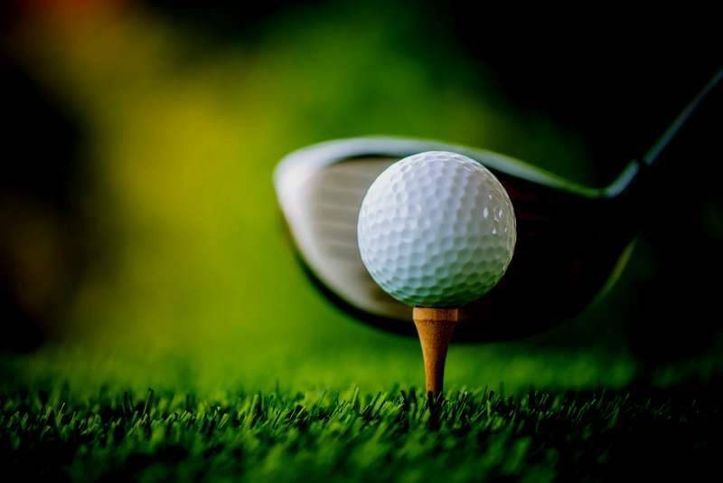 Pelota de golf sobre el tee junto a un driver